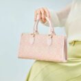 song-brocade-leather-handbag-pink-gold-dingsheng-motif-model-sitting-knee-handheld